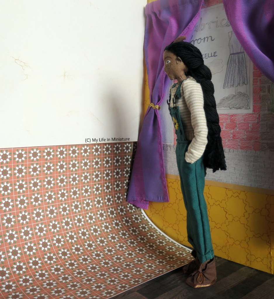 Petra stands inside Tea at Yaz's, facing the wall next to the window. Propped up on that wall are two sheets of paper; one a plain cream colour, and one with a terracotta tile design. Petra has her hands in her pockets, thinking. 