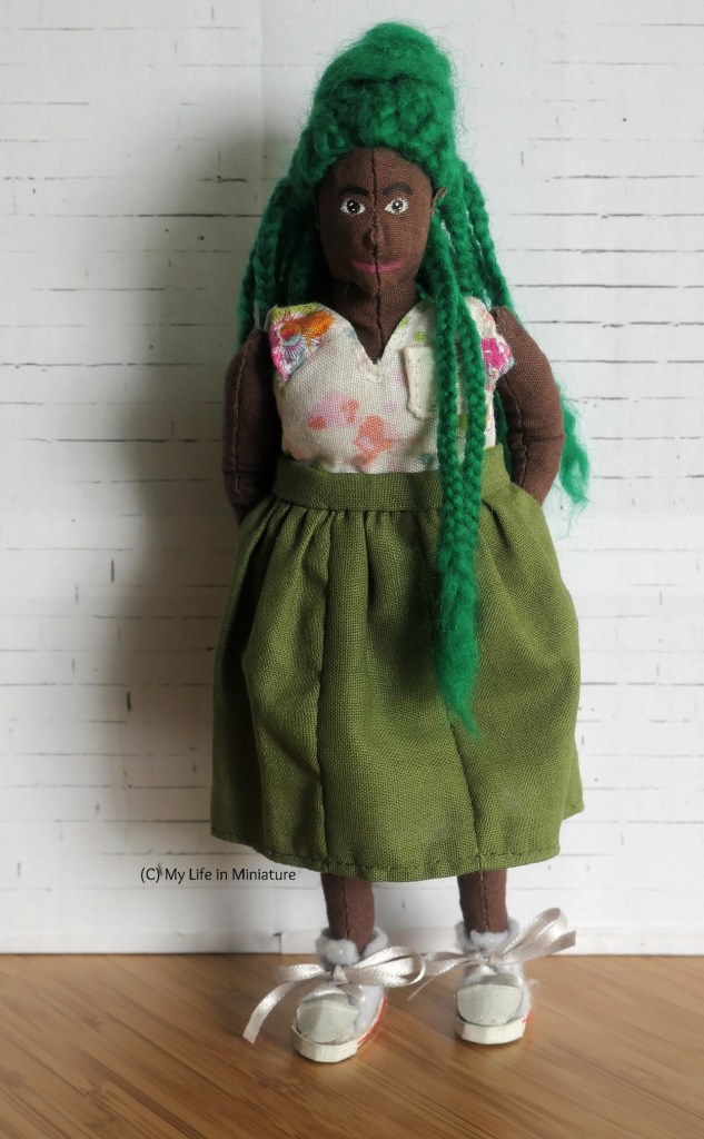Hazel wears the skirt of the khaki dress with a pink-and-white floral sleeveless shirt, while smiling at the camera. 