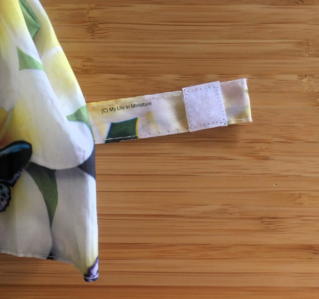 Another close-up of the umbrella closure tab. A new piece of soft Velcro has been sewn on where the old piece was, with white thread. 