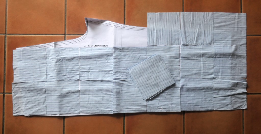 A pant pattern piece is laid flat on a terracotta tiled surface. It is mostly covered by small-ish squares of blue striped fabric, with a stack of the same squares on top.