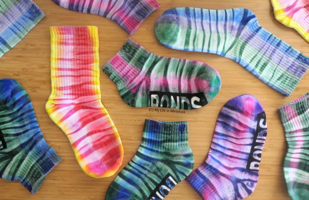 All the socks are arranged in an organised mess of a flatlay on a wood surface. 