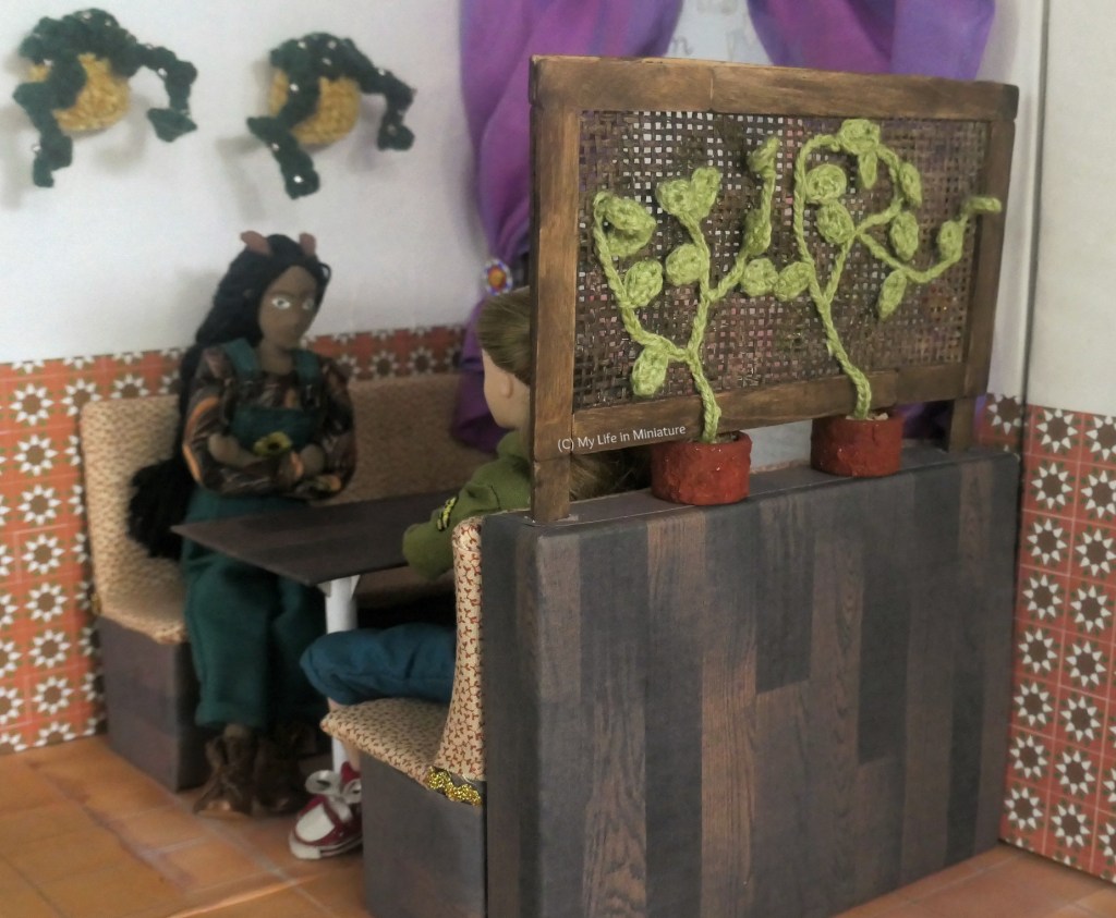 The lattice is pictured in situ in Tea at Yaz's, at the window booth. Petra and Sarah sit in the booth, having a rapid conversation. Petra faces the camera, while Sarah is partially obscured by the lattice. 