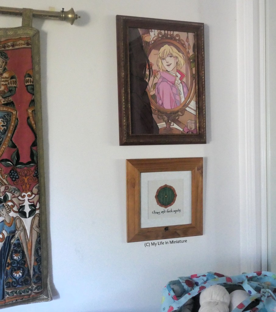 Wider shot of the wall where the stitching hangs. Around it and the portrait is the edge of a mirrored sliding door, one end of a vintage tapestry, and a small portion of the author's yarn stash. 