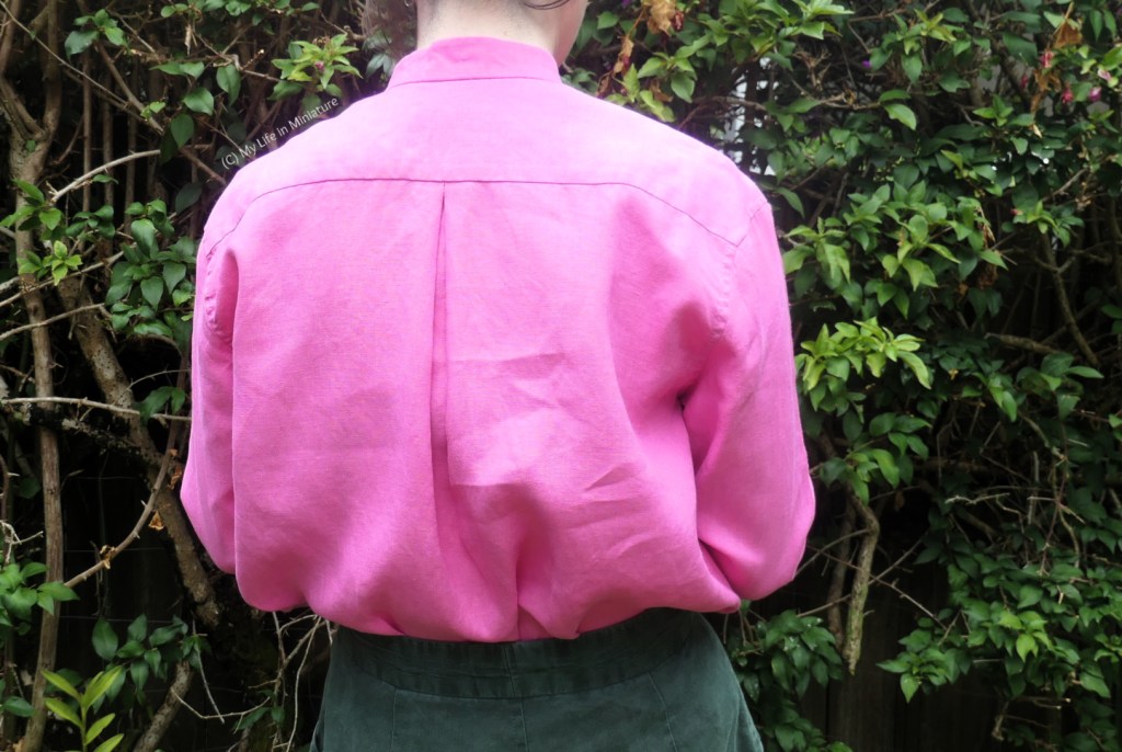 The author stands with her back to the camera, so the back of the pink shirt is visible. It is very voluminous, and has an inverted box pleat at the centre where the back meets the yoke.