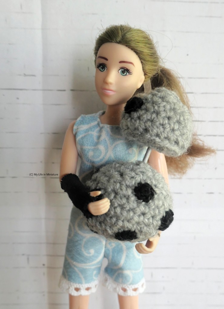 Sarah holds Chip, a circular, BB-8-esque silver android in her arms as it elevates its head to her face. Sarah's face is slightly turned away. 