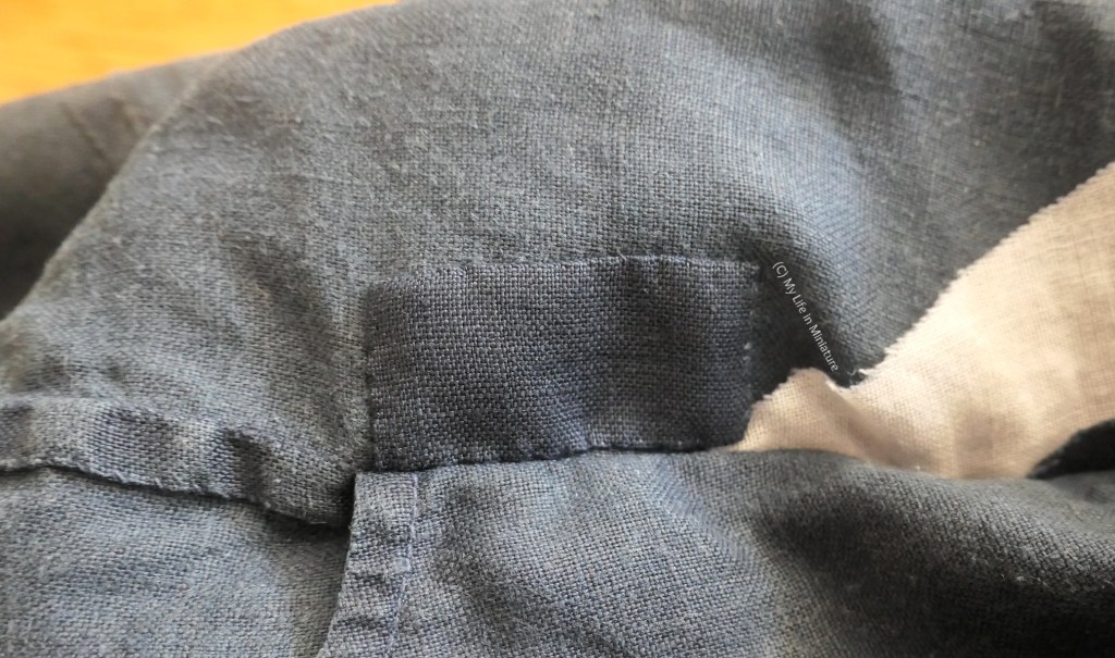 Close-up of the inside of the navy pants. The area behind where the hole was on the outside has been covered with a matching rectangular patch.