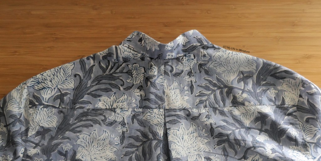 Close-up of the back shoulder and neck area of the shirt, which is laid flat on a wood surface. The centre-back yoke seam is clearer, as is the box pleat. The pattern doesn't continue smoothly from body to yoke, but it isn't too jarring.