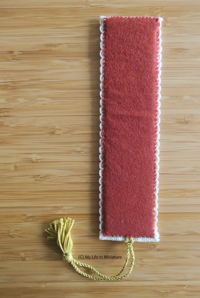 The reverse of the completed bookmark. A strip of red felt is stitched onto the back, with little scallops of the edge of the Aida poking out the sides.