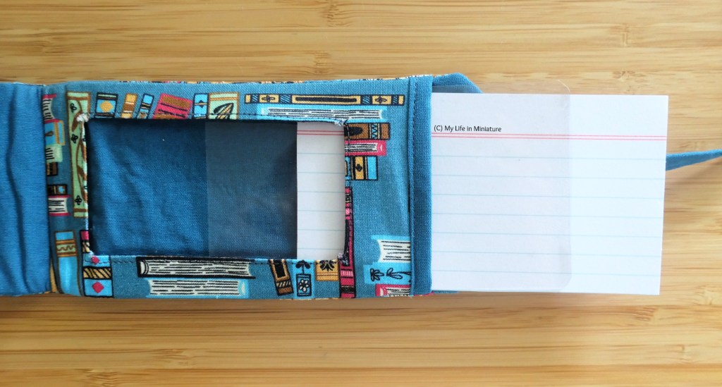 Close-up of the interior of the tag, which is plain blue with a small contrasting window. A piece of clear plastic and a blank notecard are half-inserted into the tag, behind the window.